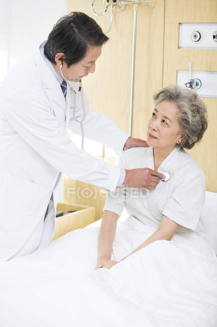 Médico chinês usando estetoscópio no paciente no hospital — Fotografia de Stock