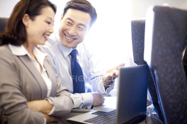 Gente de negocios chinos que trabajan con el ordenador portátil en avión - foto de stock