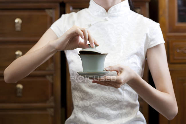 Mulher em cheongsam tradicional com xícara de chá chinês — Fotografia de Stock