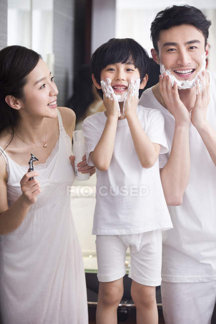 Família chinesa no banheiro com creme de barbear nos queixos — Fotografia de Stock