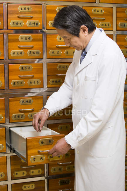 Medico cinese anziano in piedi con cassetto aperto — Foto stock