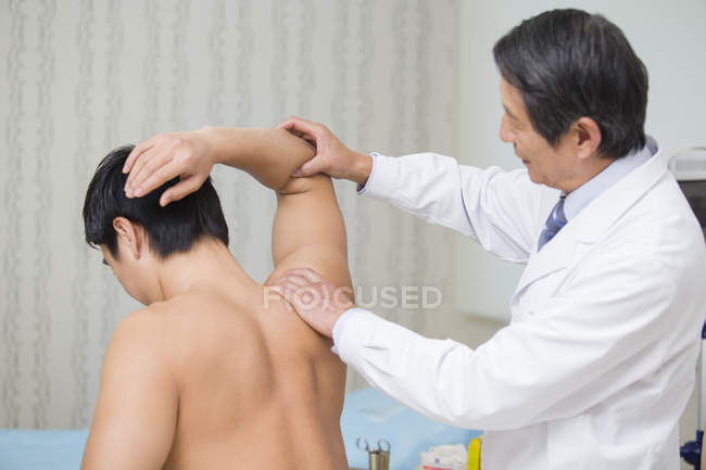Старший китайський лікар дає масаж, щоб пацієнт — стокове фото