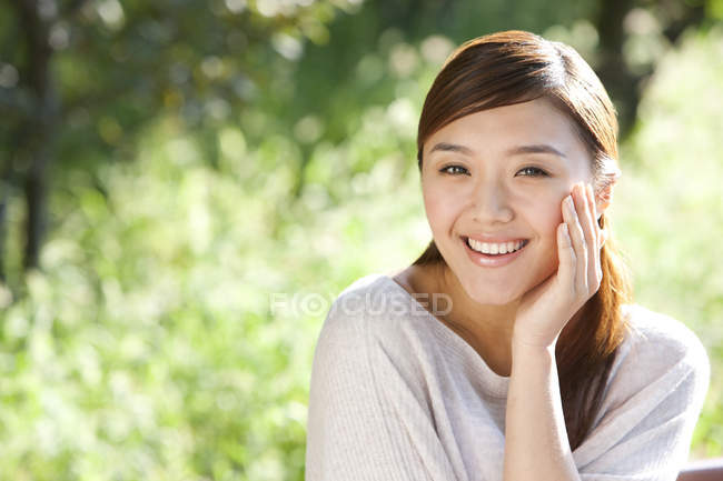 Портрет китайской женщины в парке с рукой на подбородке — стоковое фото