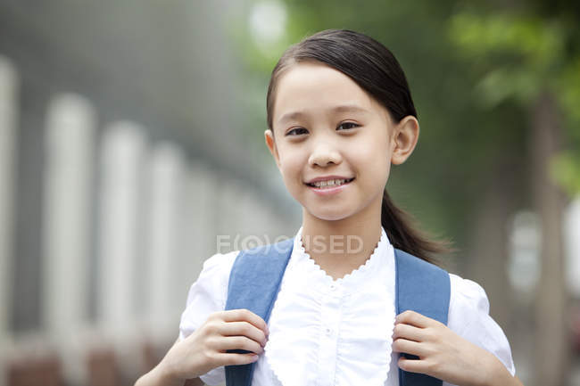 Écolière chinoise avec sac à dos regardant à la caméra — Photo de stock