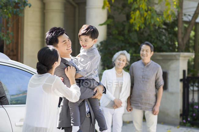 Chinese businessman holding son on street with family — Stock Photo