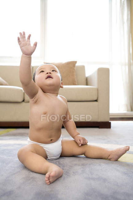 Niño chino con el brazo extendido alcanzando el suelo - foto de stock