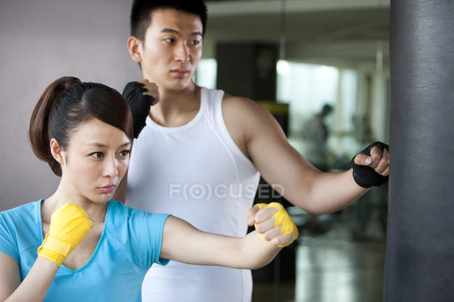 Chinese couple of athletes boxing punching bag in gym — Stock Photo