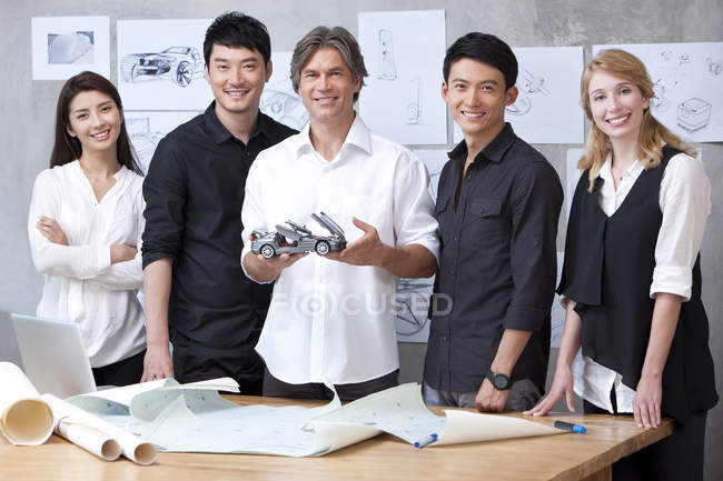 Diseñadores de coches de pie con coche modelo - foto de stock