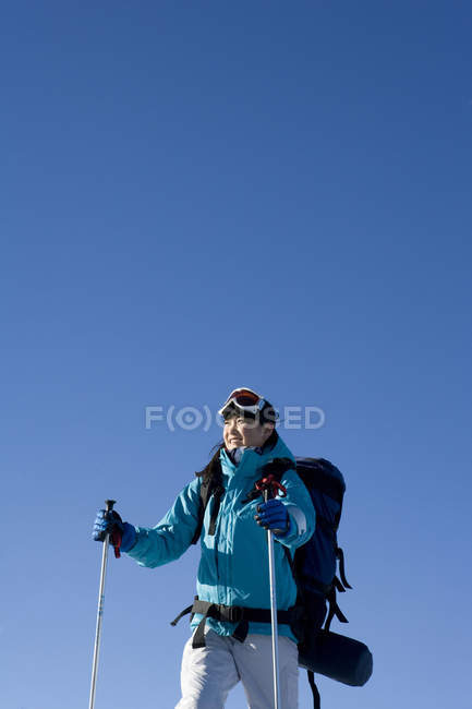 Chinesin posiert mit Skiausrüstung auf blauem Hintergrund — Stockfoto