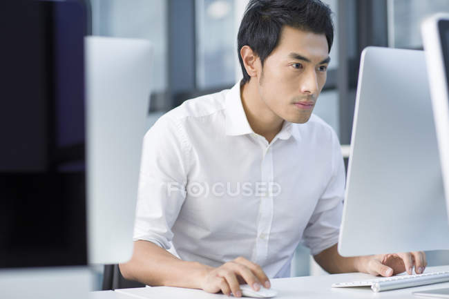 Hombre de negocios chino usando la computadora en la oficina - foto de stock