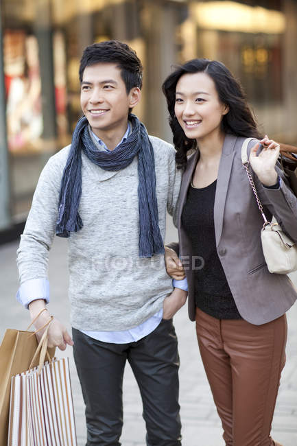 Pareja china de moda en la calle con bolsas de compras - foto de stock