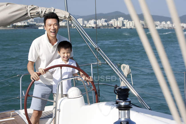 Padre e figlio cinese che navigano su yacht nella baia — Foto stock