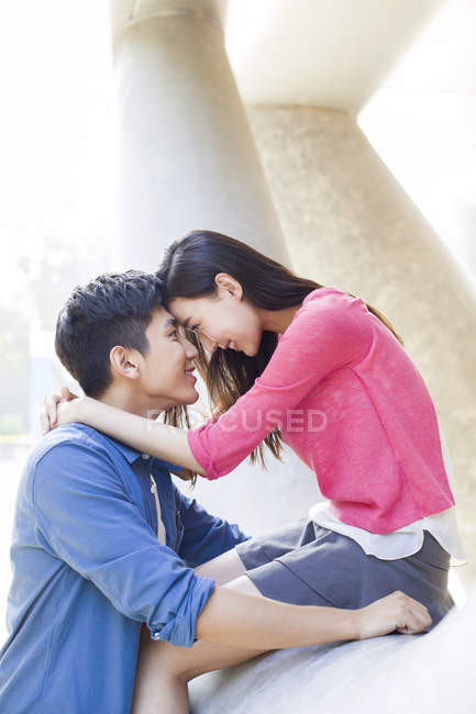 Casal chinês sentado cara a cara e abraçando na rua — Fotografia de Stock
