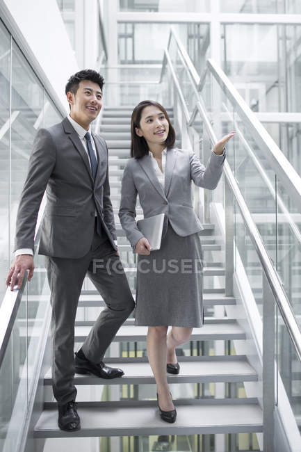 Chinese business people talking on stairs — Stock Photo