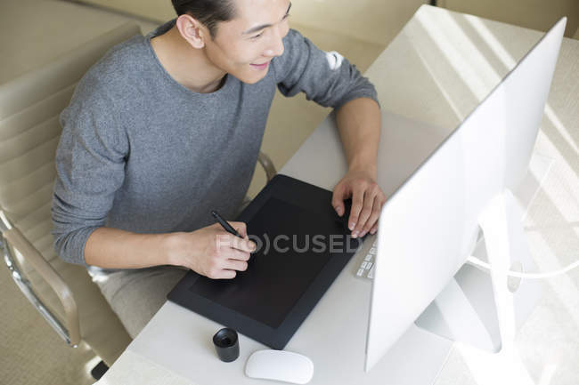 Illustratore maschio cinese che fa schizzo su tablet disegno — Foto stock
