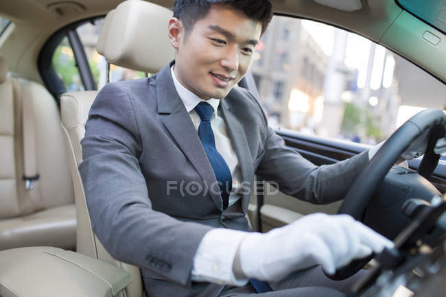 Chauffeur chinois utilisant un smartphone en voiture — Photo de stock