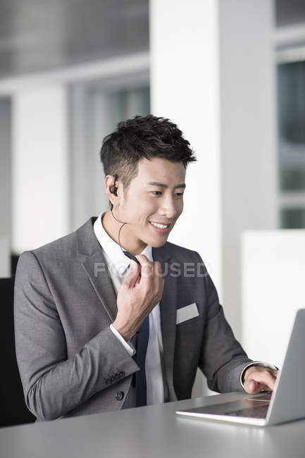 Gerente de venta chino con auriculares usando computadora portátil - foto de stock