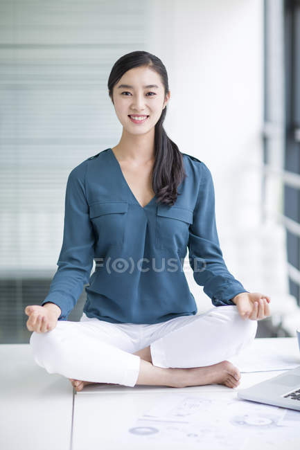 Mujer china meditando en la mesa de la oficina - foto de stock