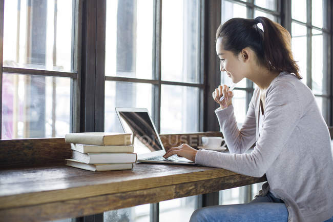 Китаянка учится с ноутбуком в кафе — стоковое фото