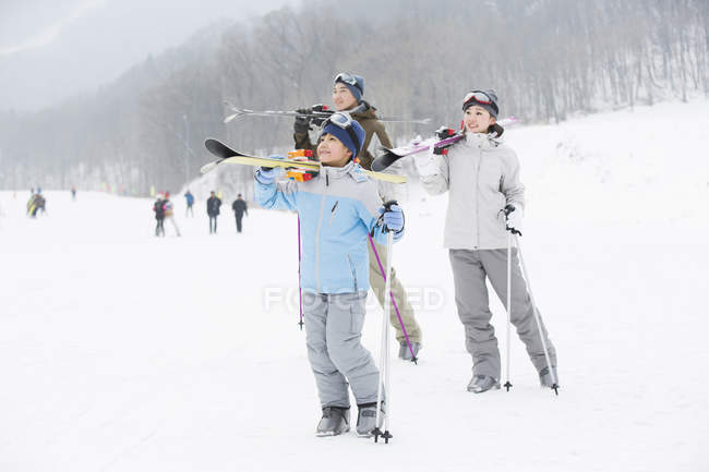 Parents chinois avec fils portant des skis sur les épaules dans la station de ski — Photo de stock