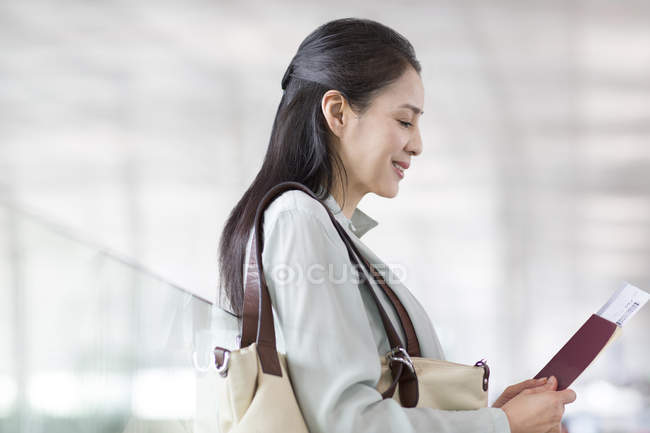 Mulher chinesa esperando no aeroporto com bilhete — Fotografia de Stock