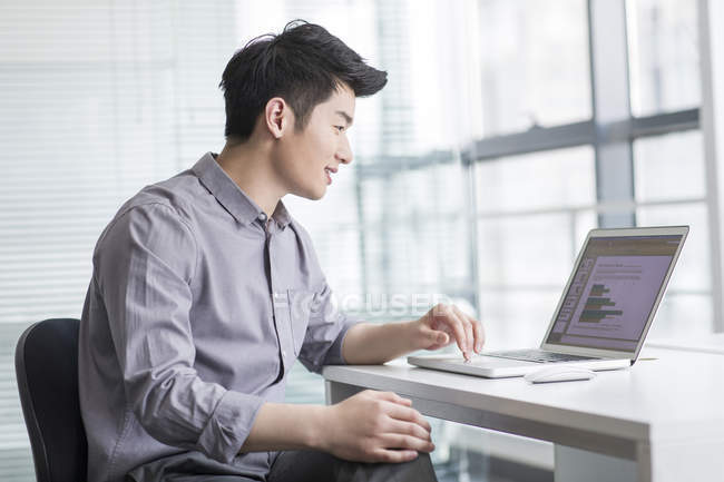 Chinese businessman using laptop in office — Stock Photo