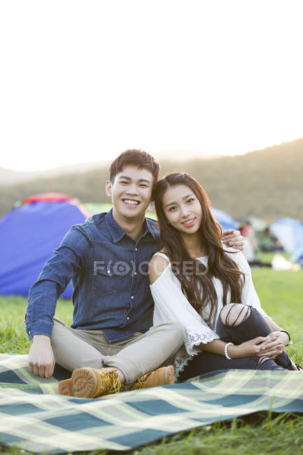 Chinese couple sitting on music festival lawn — Stock Photo