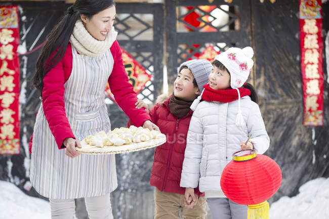 Mãe e irmãos com bolinhos chineses tradicionais na aldeia — Fotografia de Stock