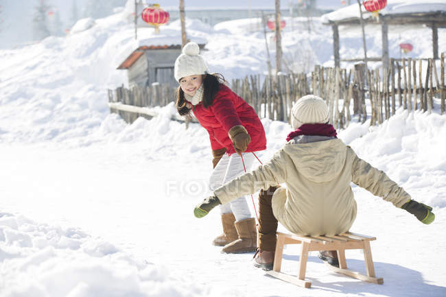 Китайские дети играют с санями в снегу — стоковое фото