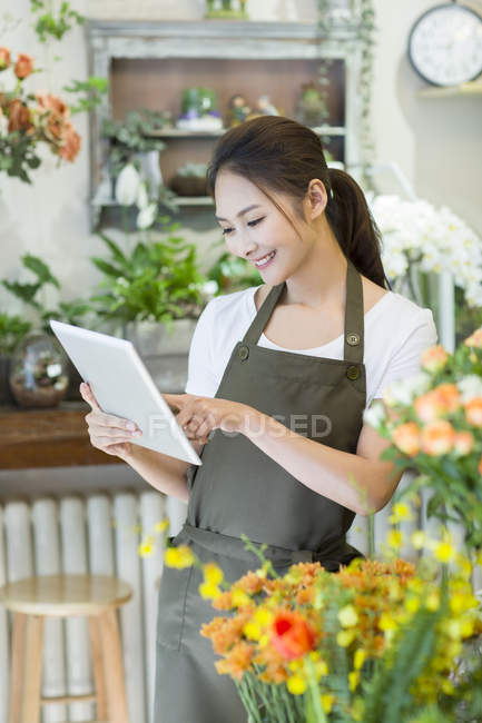Floristería china usando tableta digital en la tienda - foto de stock