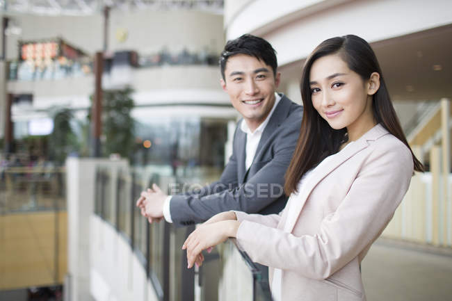 Chinese couple standing in shopping mall and looking in camera — Stock Photo