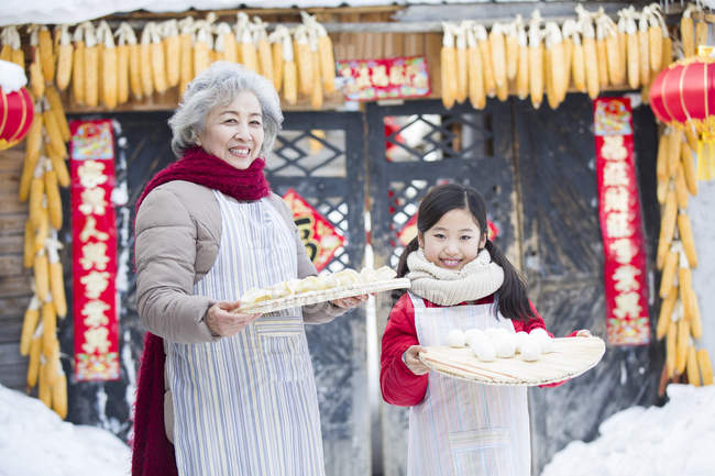 Grandmother and granddaughter posing with Chinese dumplings — Stock Photo