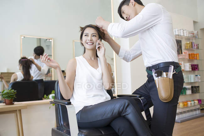 Chinese woman talking on phone in barber shop — Stock Photo