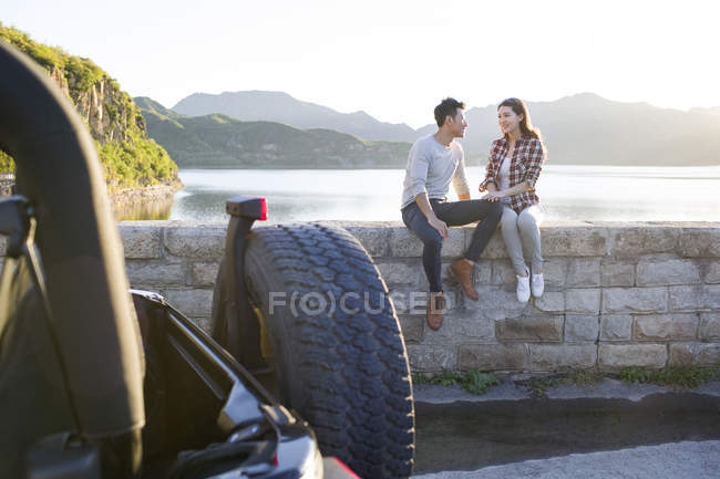 Pareja china sentada junto al lago en los suburbios - foto de stock