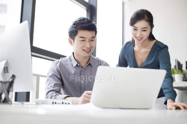 Chinese business co-workers using laptop — Stock Photo