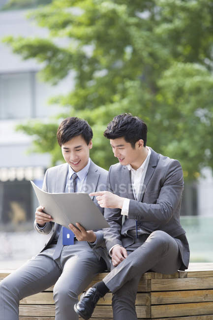 Chinese businessmen working with documents on street — Stock Photo