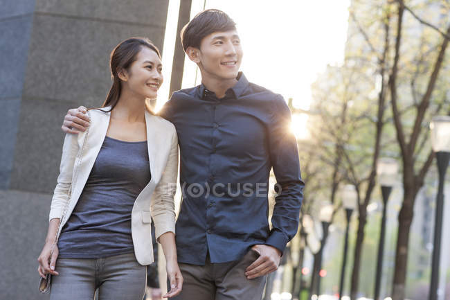 Китайская пара идет по тротуару в городе и смотрит в сторону — стоковое фото