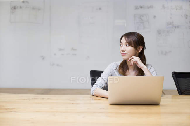 Китаянка сидит с ноутбуком в бортовой комнате — стоковое фото