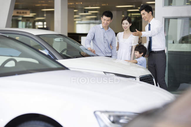 Família chinesa com filho escolhendo carro com revendedor — Fotografia de Stock