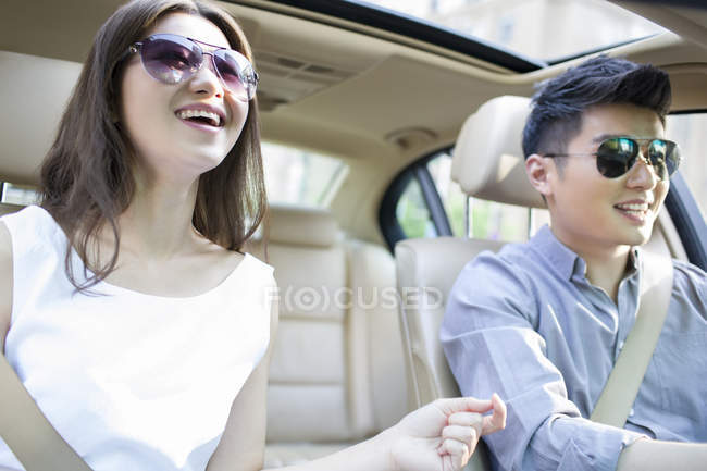 Pareja china montando en coche y sonriendo - foto de stock