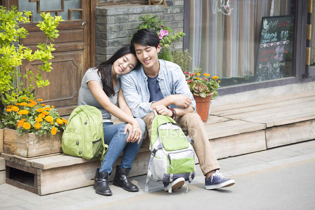 Китайська пара, відпочиваючи на вулиці з рюкзаками — стокове фото