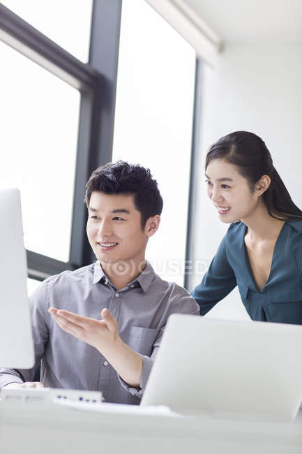 Compañeros de negocios chinos discutiendo el trabajo en la oficina - foto de stock
