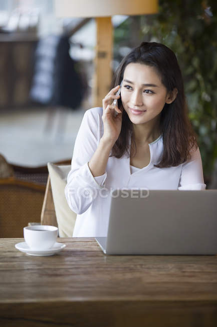 Chinese woman talking on phone in cafe — Stock Photo