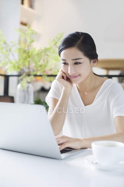 Femme chinoise utilisant un ordinateur portable dans un café — Photo de stock