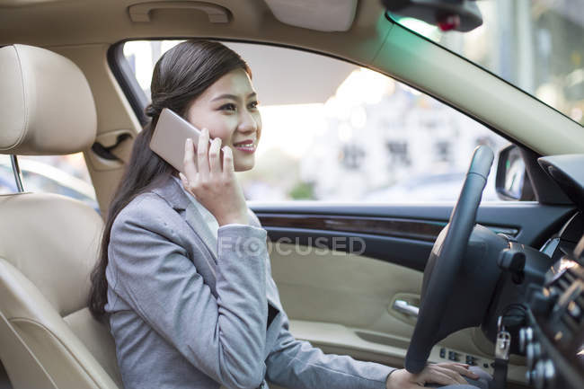Chinese woman talking on phone in car — Stock Photo