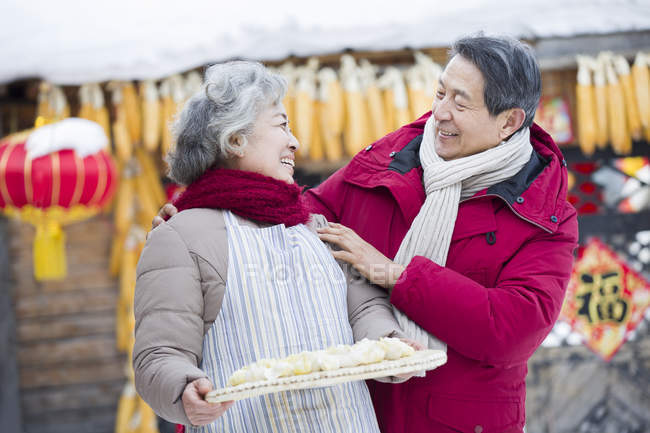 Senior couple standing with dish of traditional dumplings — Stock Photo