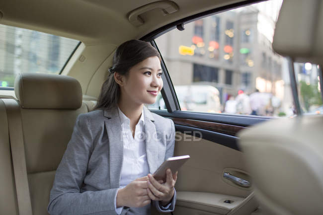 Empresária chinesa segurando smartphone no carro — Fotografia de Stock