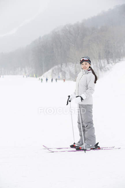 Chinese female skier standing with skis on slope — Stock Photo