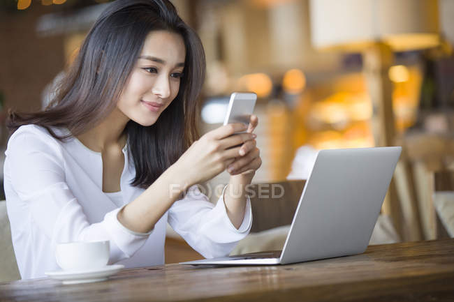 Chinese woman using smartphone in cafe — Stock Photo