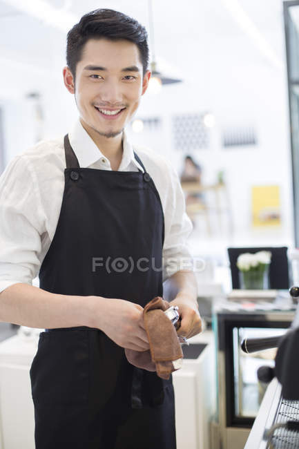 Chinese barista wiping appliance in coffee shop — Stock Photo